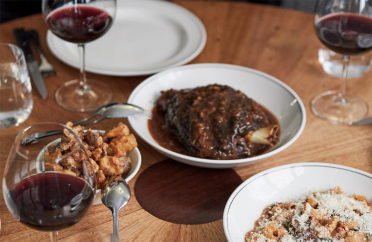 meat and pasta sitting on the table with wine