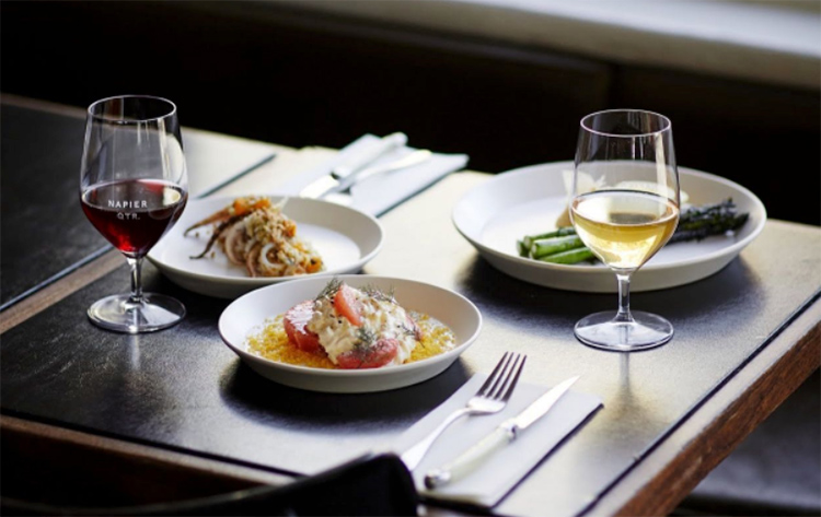 wine and pasta sitting on the table with knives and fork