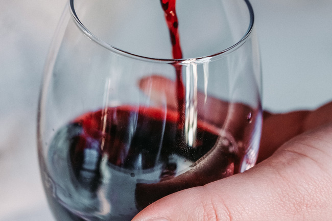Person pouring glass of red wine
