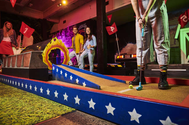 smiling people playing mini golf and having fun