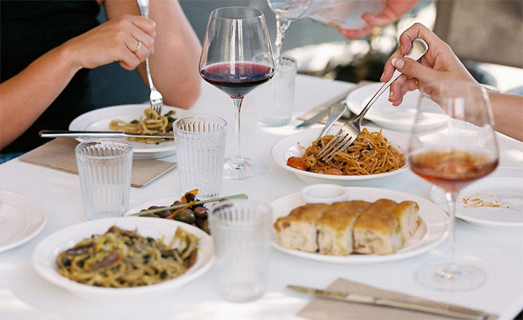 two people enjoying italian food and wine sitting on a table