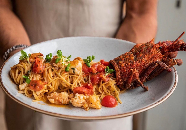 a seafood pasta platter being held by a waitress