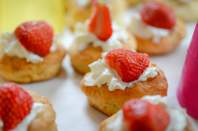 a selection of strawberry muffins resting on a dollop of fresh cream