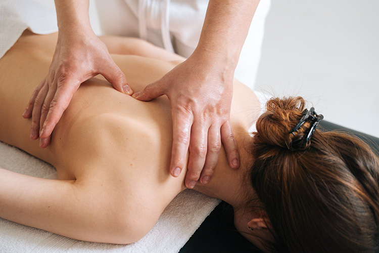 a lady lying on a massage table receiving a massage by a therapist