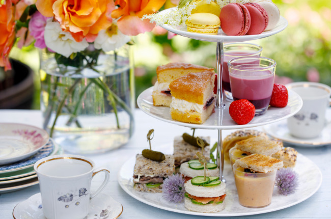 a pile of colourful macarons and cakes next to beautiful flowers