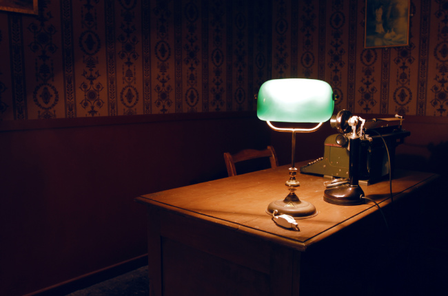 a lamp on an old desk in a dark puzzle room