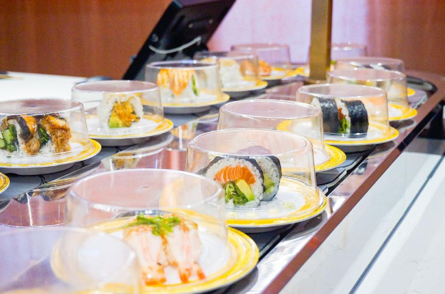 rows of plates of sushi on a conveyor belt