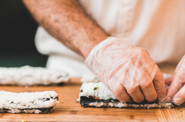 a sushi master preparing a roll of sushi