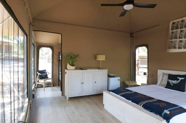 a huge bed and ceiling fan inside a glamping tent