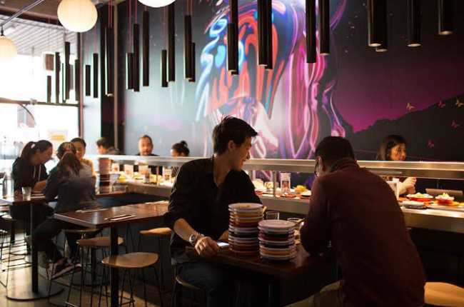 patrons eating plates of sushi in a sushi train restaurant