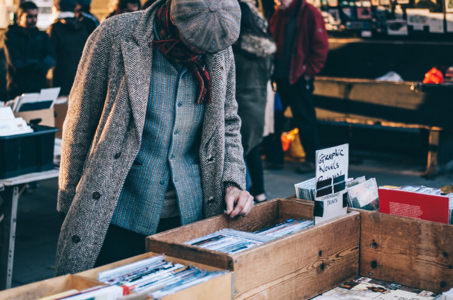 man looking through a collection of novels
