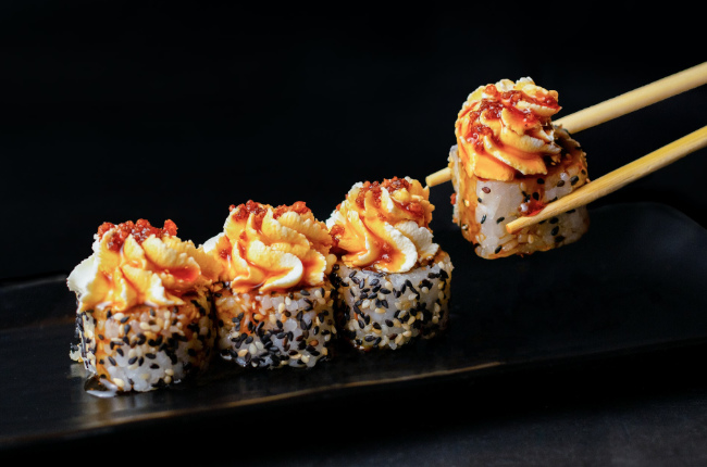 sushi topped with whipped cream cheese and spicy sauce