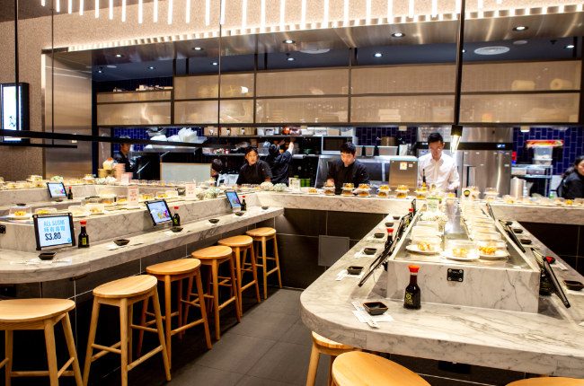 the inside of a sushi train restaurant with rows of tables