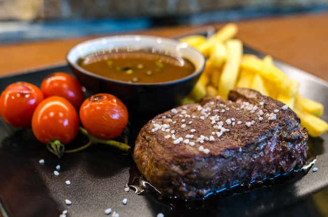 a juicy piece of steak with chips and cherry tomatoes