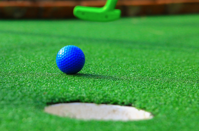 a golf ball about to be putt into a hole