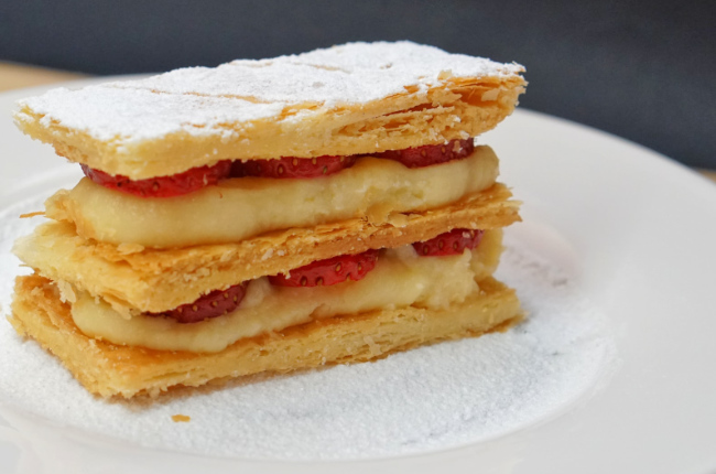 layers of pastry in between cream and strawberries