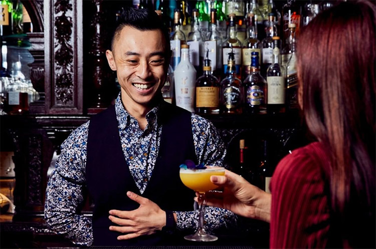 a bartender serving a woman a cocktail at marble bar sydney