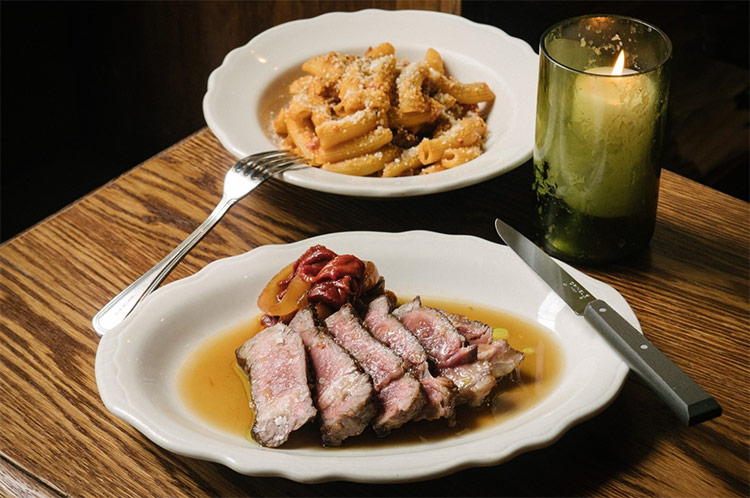 two meals sitting on a dining table beside a candle at albertos lounge