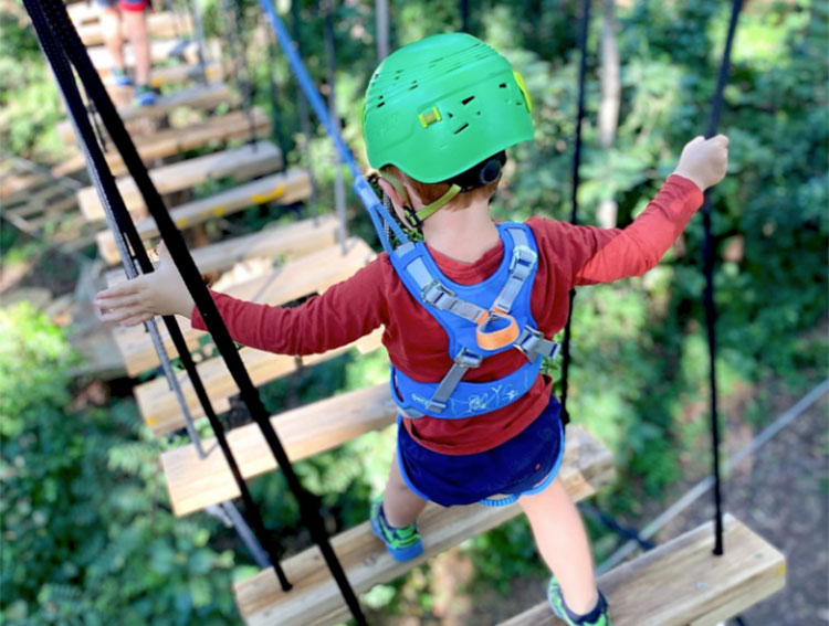 a close up of a kid walking across the largest zipline attraction in mt tamborine