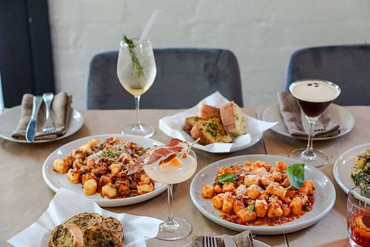 a table filled with pasta meals and cocktails at mammas boy trattoria in melbourne