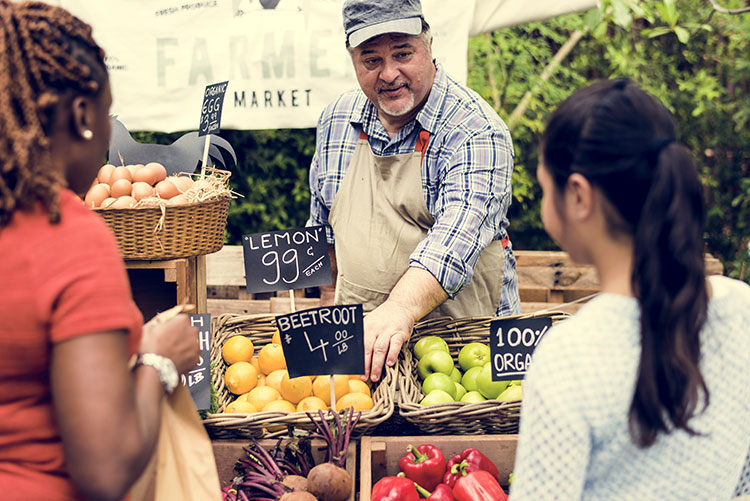 two women standing at a farmers market