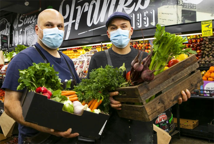 two men standing with a box of fresh veggies in their hands from south melbourne market