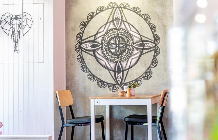 two seats and a coffee table sitting below a mural of an elephant