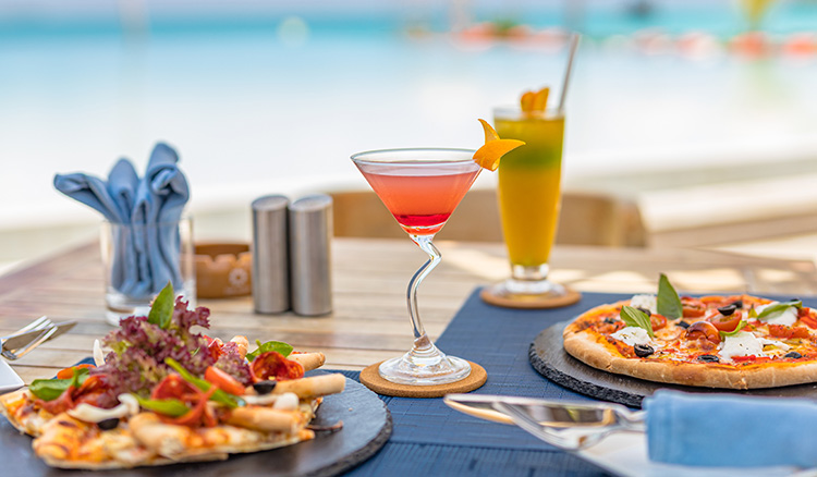 pizza and cocktails sitting on the table outside