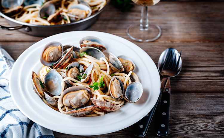 a bowl of oysters on a table with wine