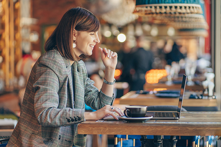 a woman sitting at her laptop at a cafe