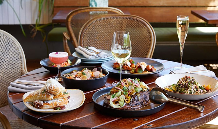 an array of dishes sitting on a table at a restaurant with champagne