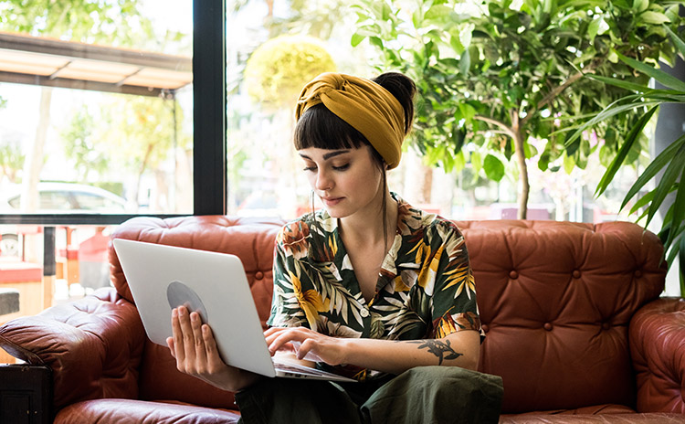 a woman sitting on a red couch with her laptop